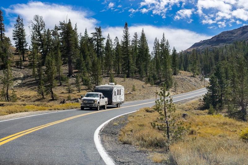 September 29, 2018 Dardanelle / CA / USA - Truck towing a camper on the highway through the Sonora Pass on a sunny day, Sierra mountains