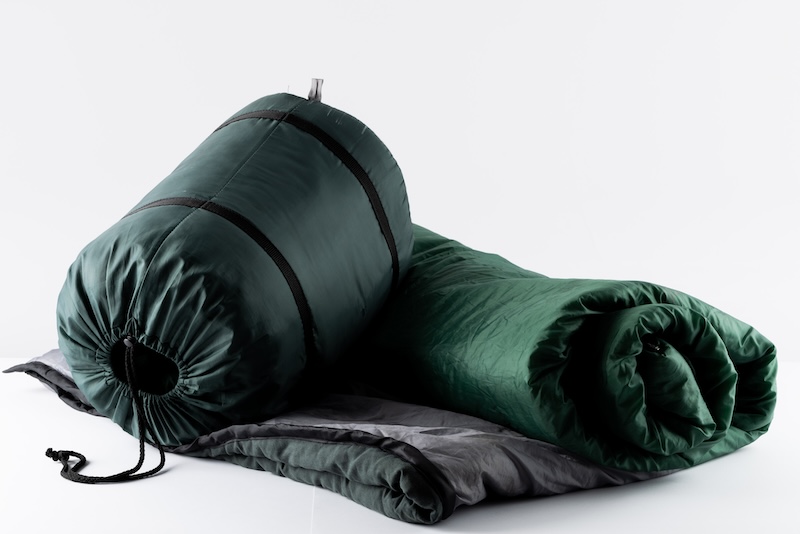 Close up of sleeping bag on white background with copy space. National camping month, equipment and celebration concept.