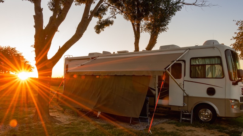 Rv motorhome camping with trees and sunburst with awning out on rv