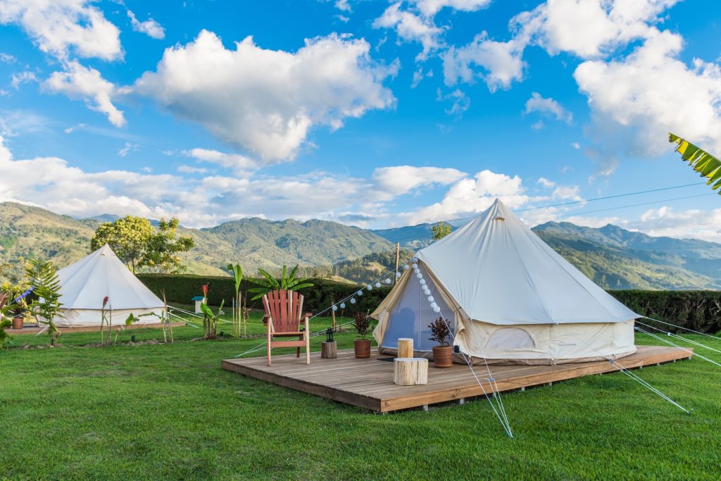 Two glamping sites on a sunny day with a beautiful mountain landscape in the background and a spectacular blue sky. Glamorous Camping